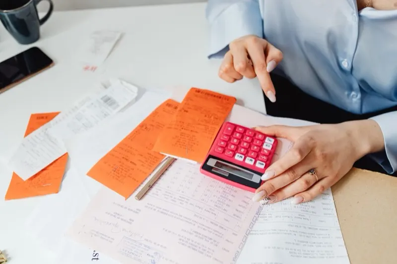 Justificatifs de frais professionnels et calculatrice sur un bureau, avant numérisation dans un logiciel de notes de frais