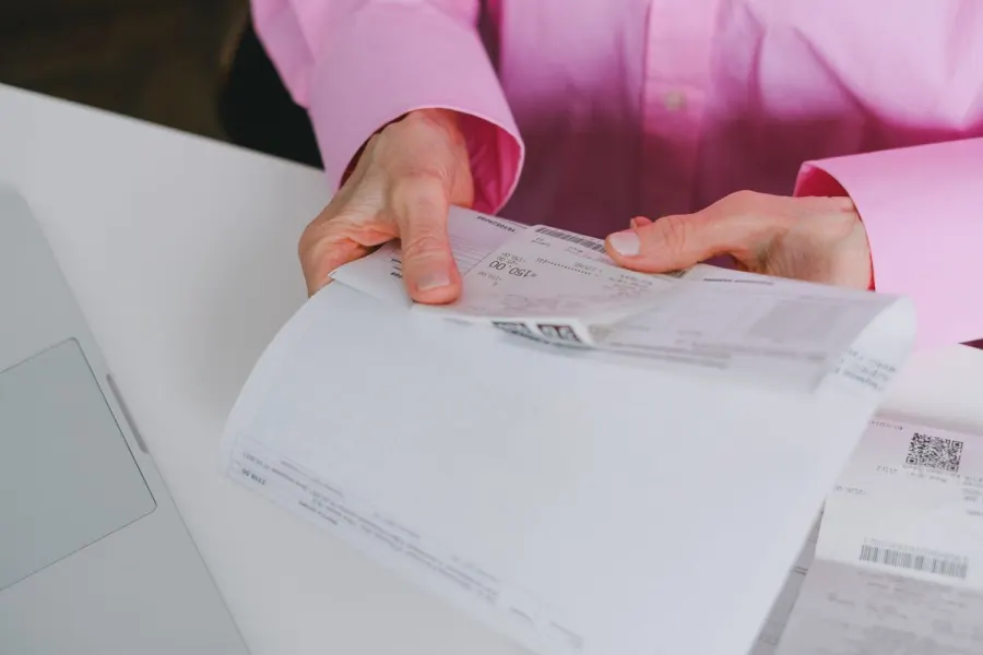 Tickets et reçus de dépenses professionnelles classés sur un bureau avant saisie de la note de frais