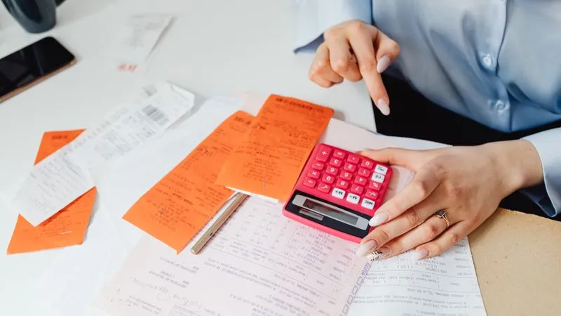Justificatifs et calculatrice sur un bureau, préparation d'une note de frais