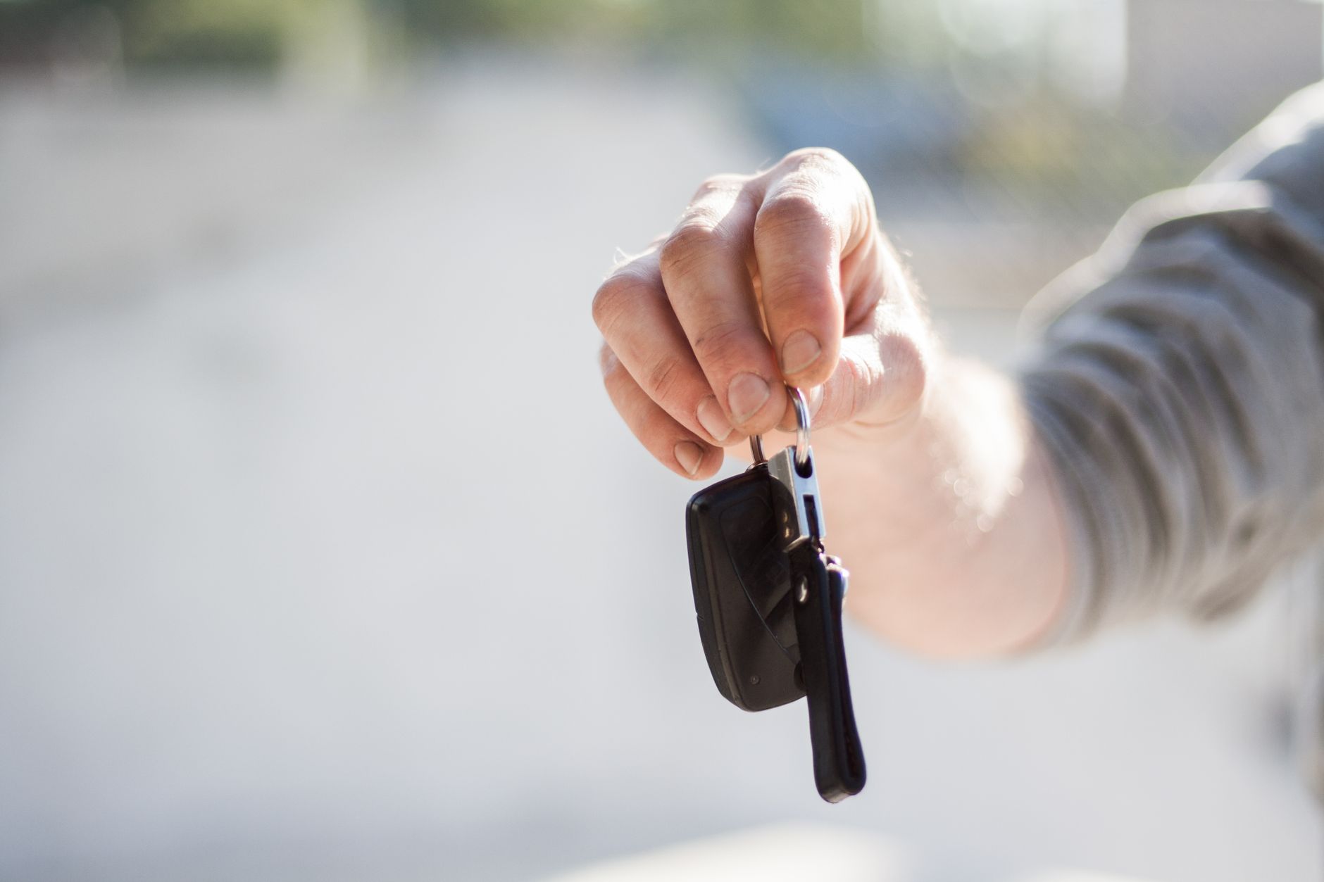 main tendant la clé d'une voiture de location au moment de la remise du véhicule