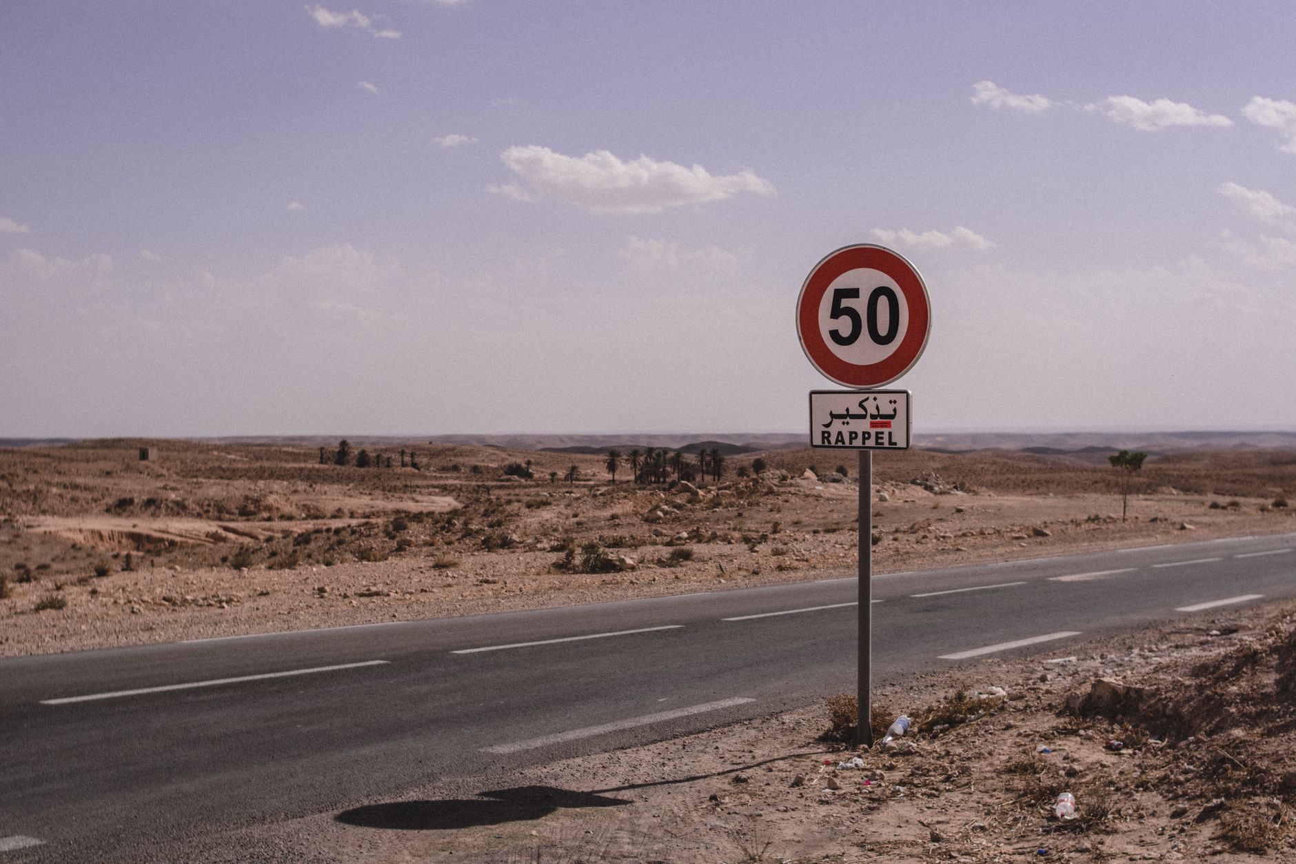 route tunisienne bordée de terres sèches avec un panneau de limitation à 50 et un panonceau Rappel en arabe et en français