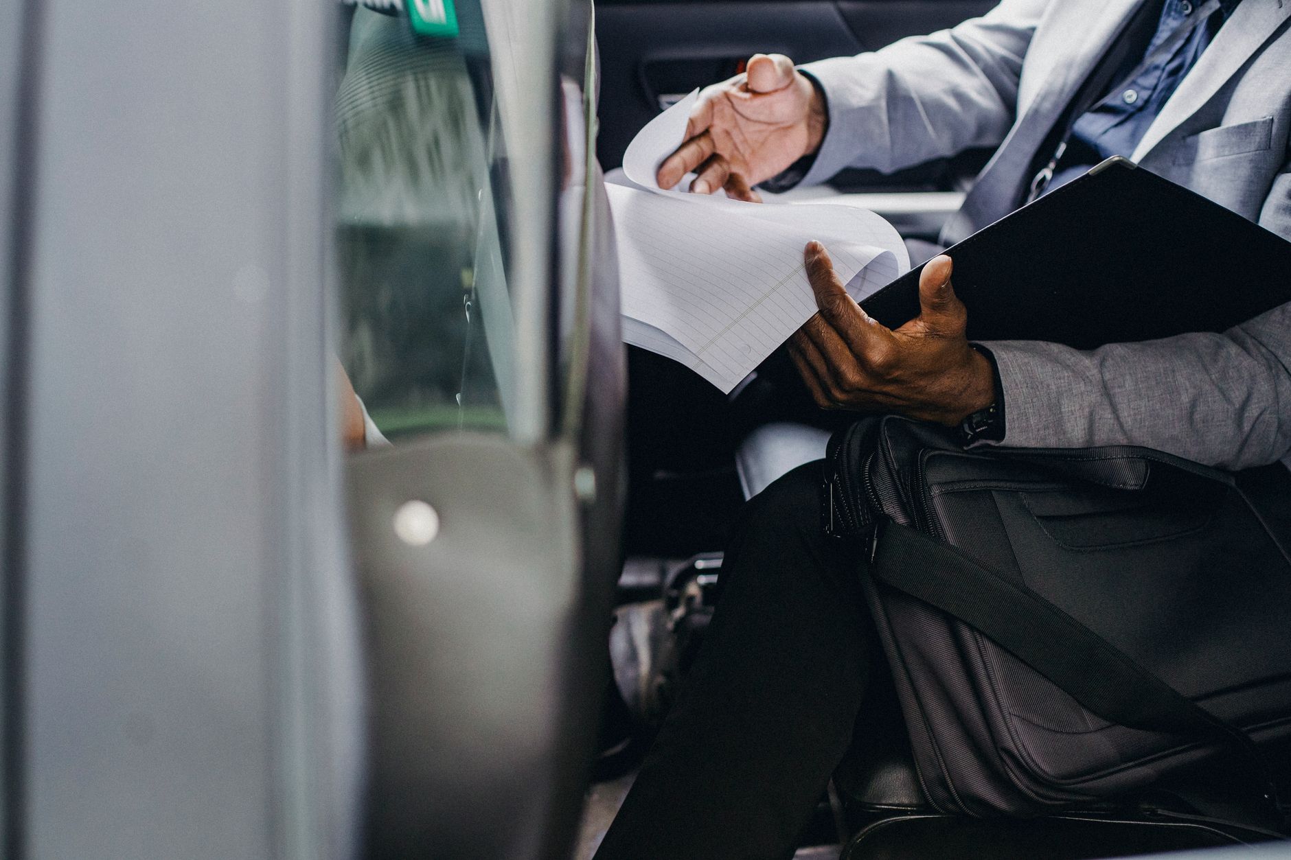 voyageur en costume relisant ses documents assis dans une voiture, un porte-documents sur les genoux