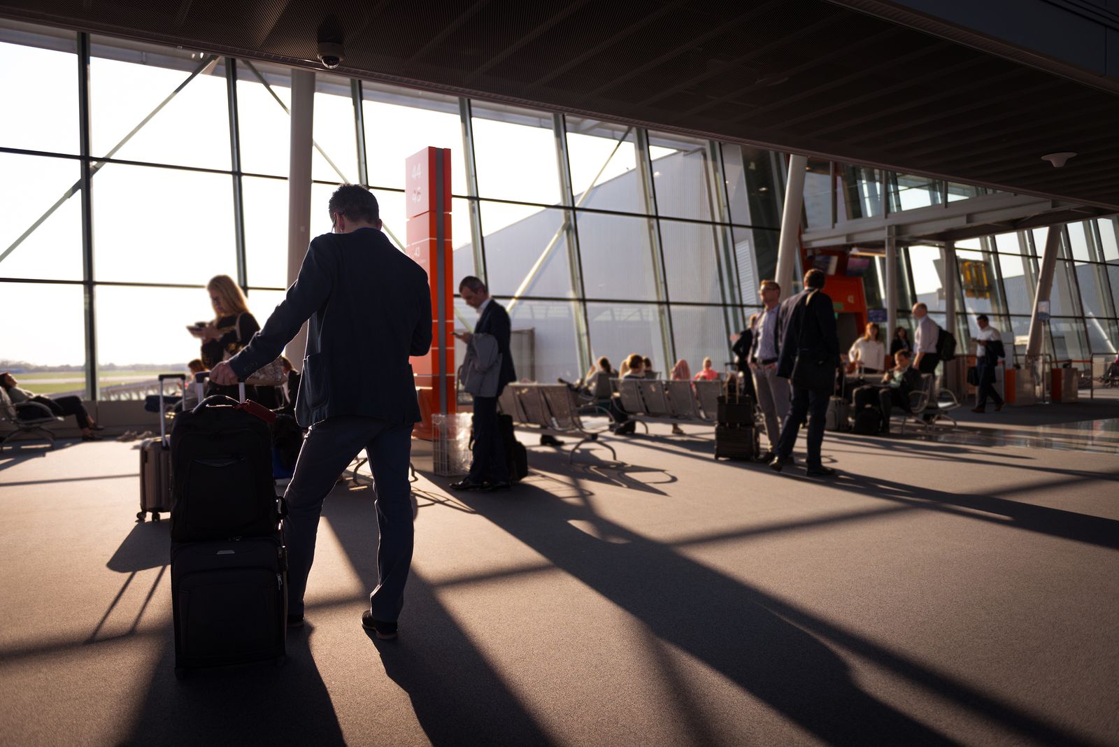 voyageur d'affaires avec une valise cabine à la sortie d'un terminal d'aéroport