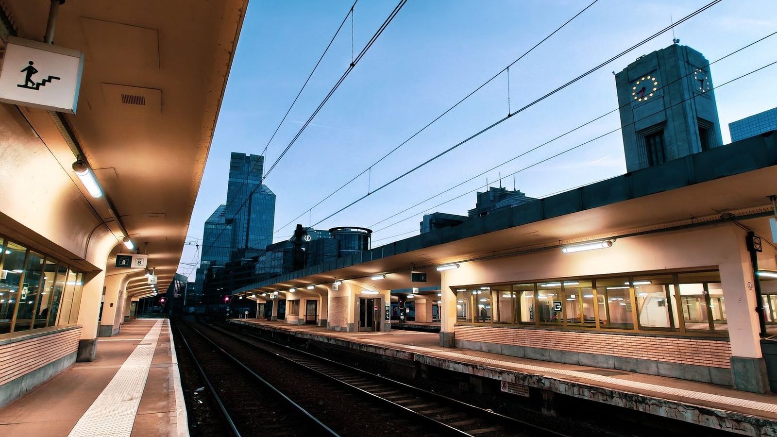 Quai de gare à Bruxelles au crépuscule, avec la tour de l'horloge