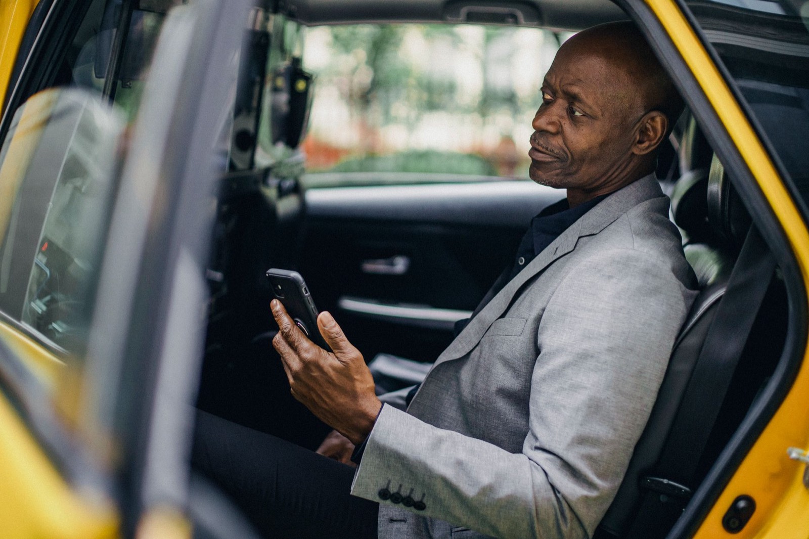 Homme d'affaires réservant un VTC depuis son smartphone